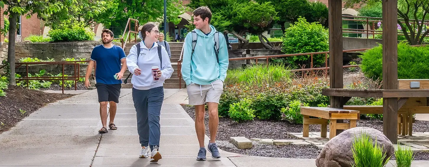 Four students walking outside away from the library